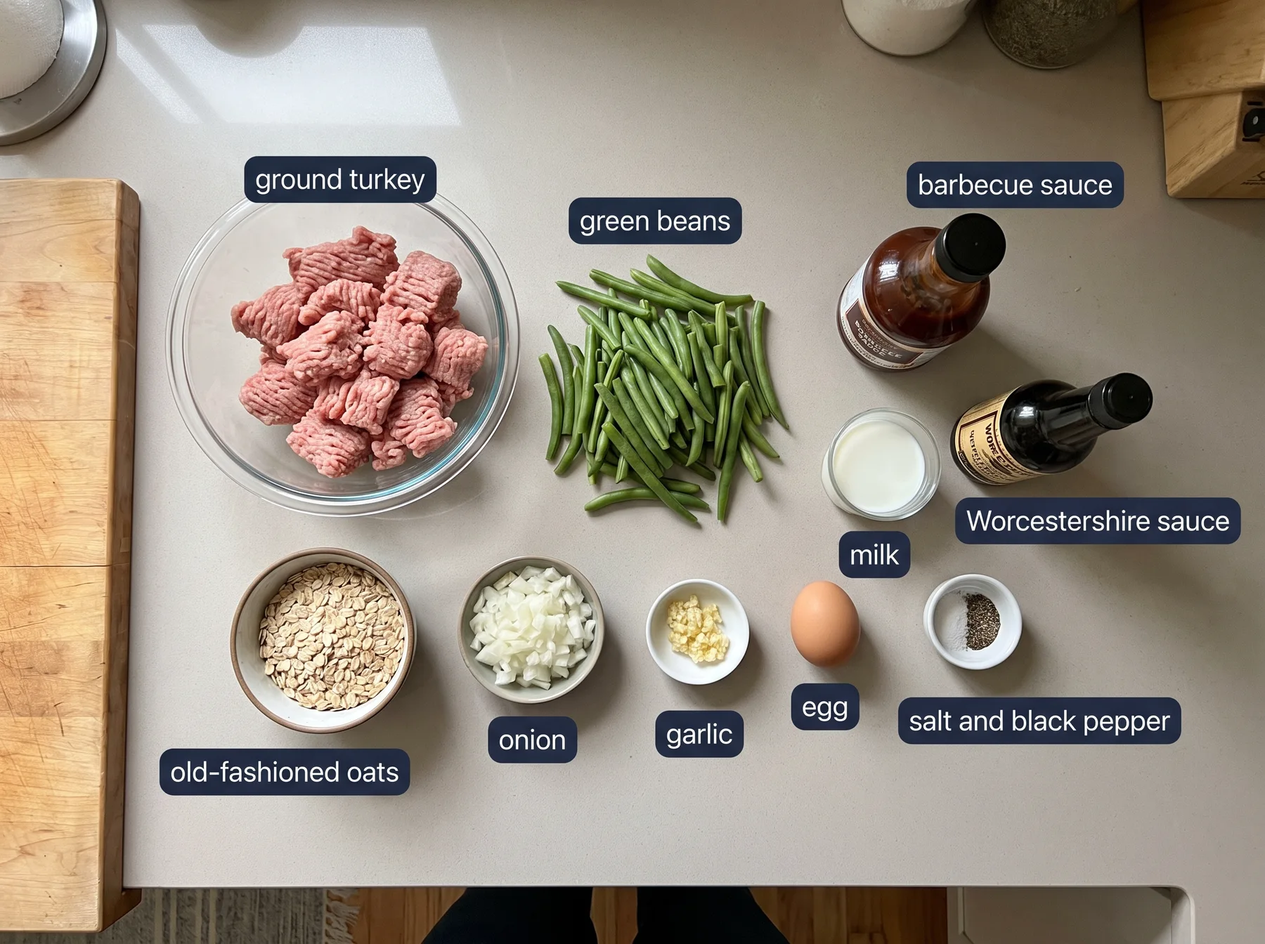 Overhead view of labeled turkey meatloaf ingredients including ground turkey, green beans, sauces, oats, onion, garlic, egg, and seasonings.