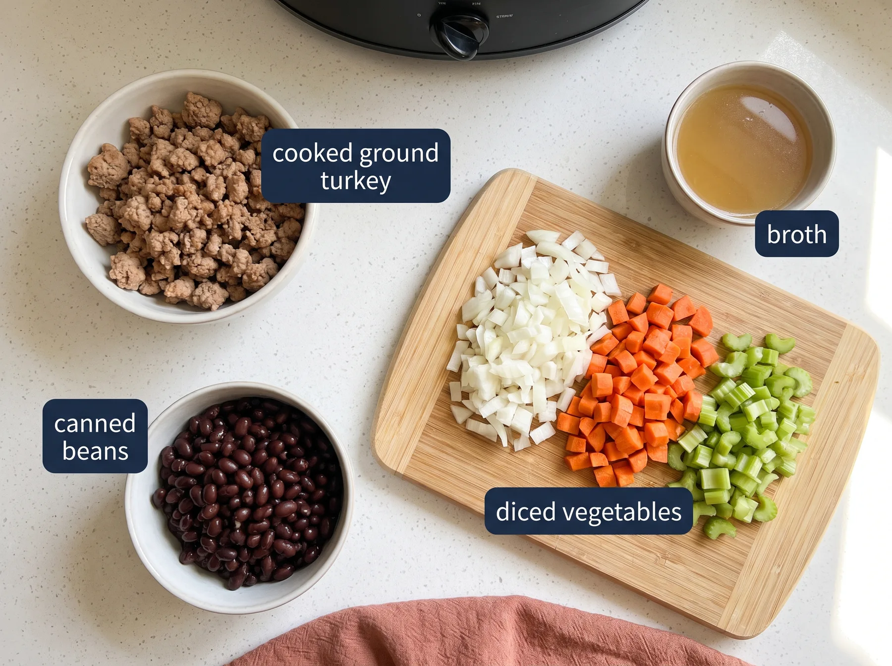 Overhead view of cooked ground turkey, canned beans, broth, and diced vegetables for slow cooker soup.